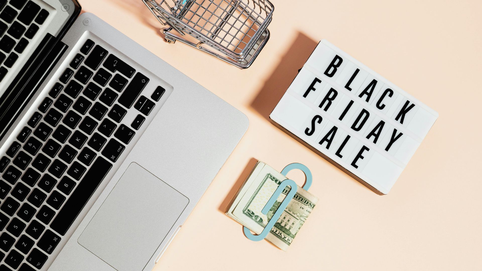 Top View of Silver Macbook Beside a Shopping Cart and Black Friday Sale Signage (Image via Kaboompics.com)