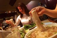 Aubri Bitterolf (CQ), left, of Santa Monica, enjoys a steaming hot bowl of Pho Bo, a Vietnamese beef - Source: Getty