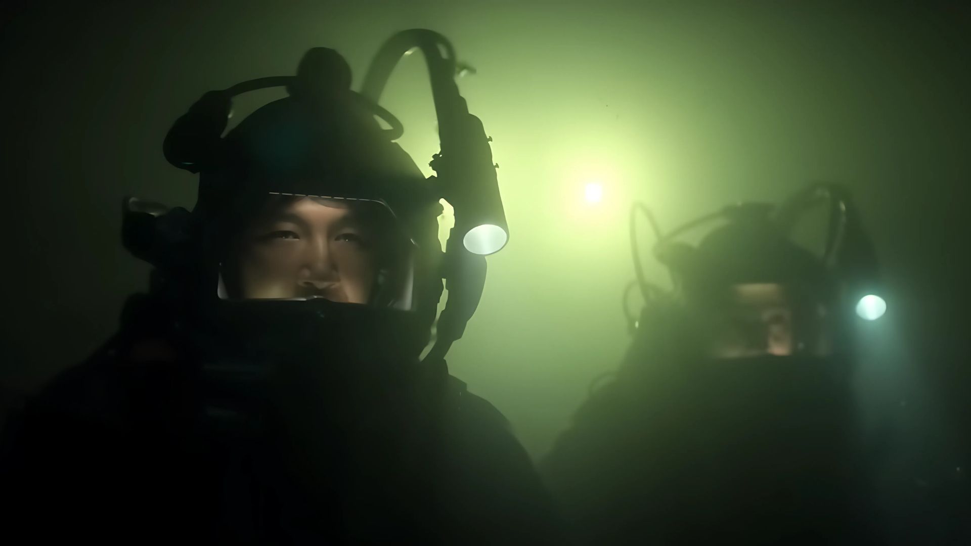 Two divers with lights on under water