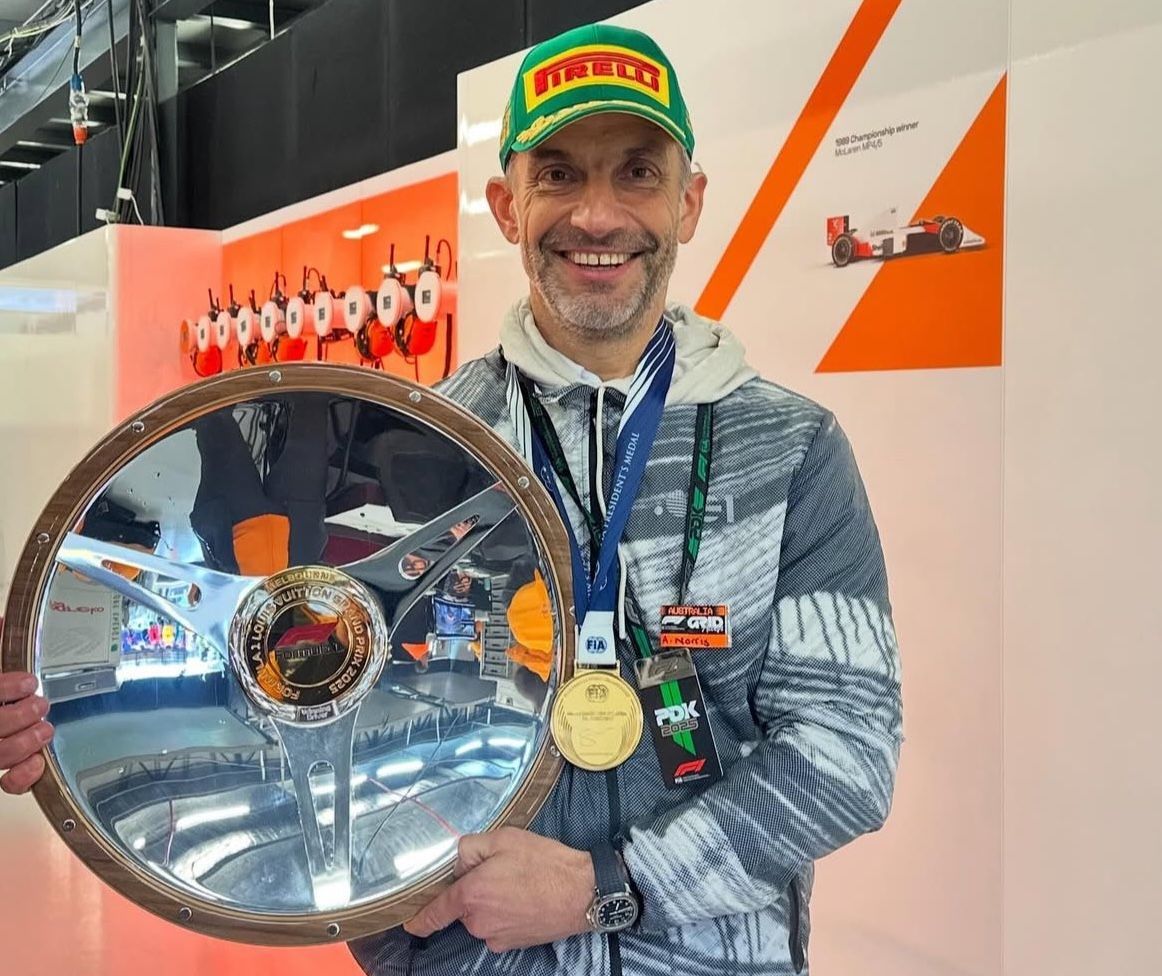 Formula 1 driver Lando Norris&#039; father, Adam Norris, wears his medal and podium cap as he holds Lando&#039;s Australian Grand Prix trophy. (Image via X/@ln4norris)