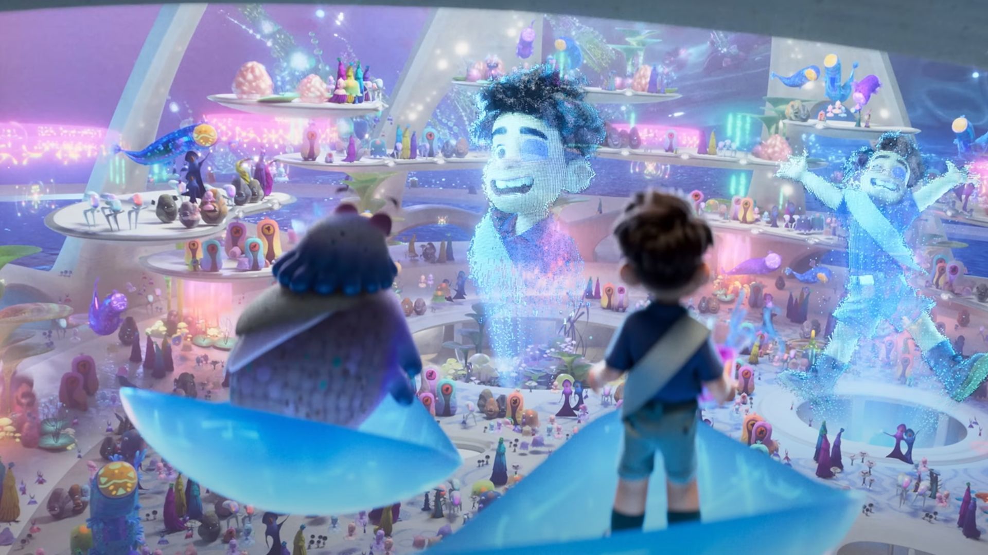 Elio watches his large projections amid a crowd of aliens below them
