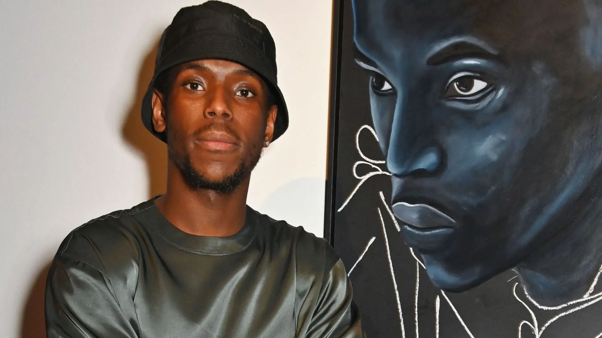 Micheal Ward poses in front of a portrait of himself at the opening night of Netflix