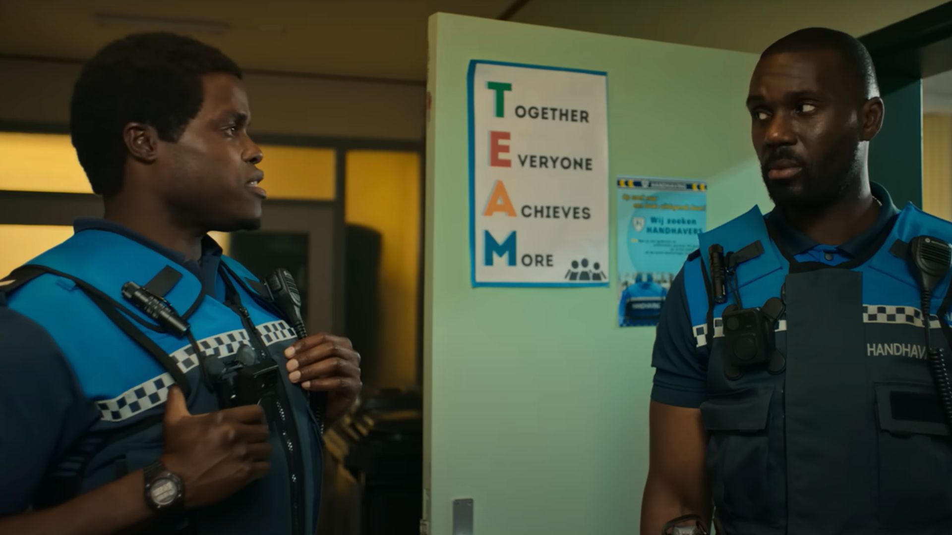 A dumb cop jokes and a responsible cop watches him with a serious expression on his face