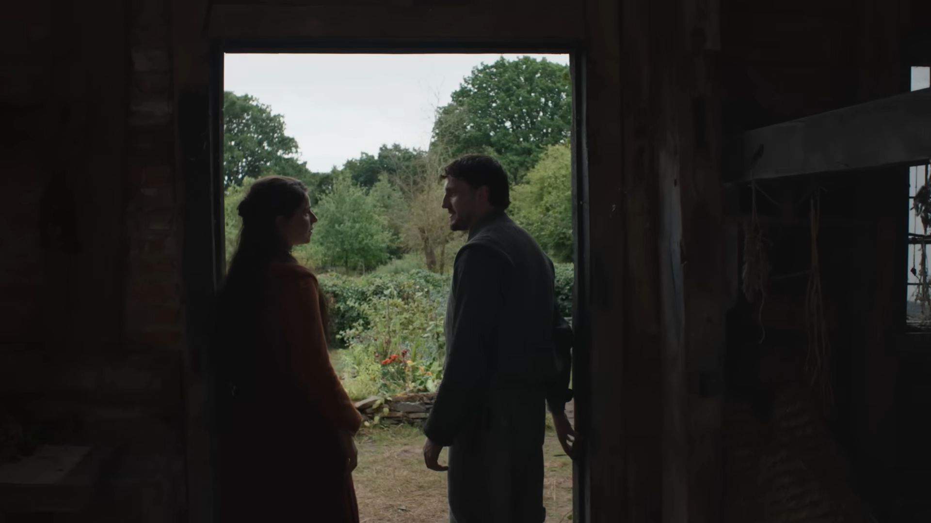 Agnes and William standing on a door, looking at each other in a still from Hamnet