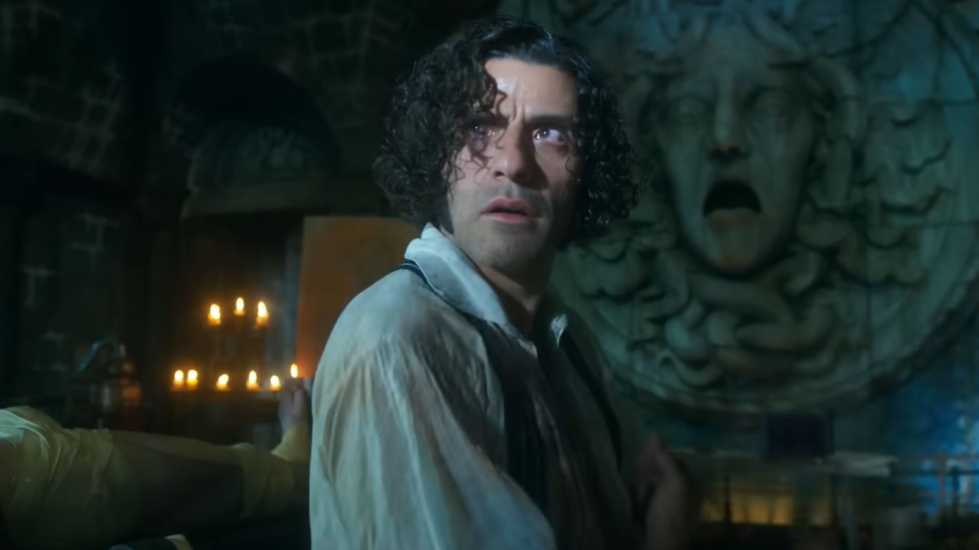 Victor Frankenstein looks back as white light glows up his face from thunderstorms outside