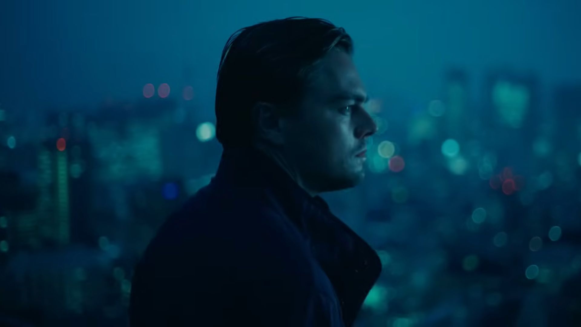 Cobb (Leonardo DiCaprio) in a close up and the entire city is visible in the background