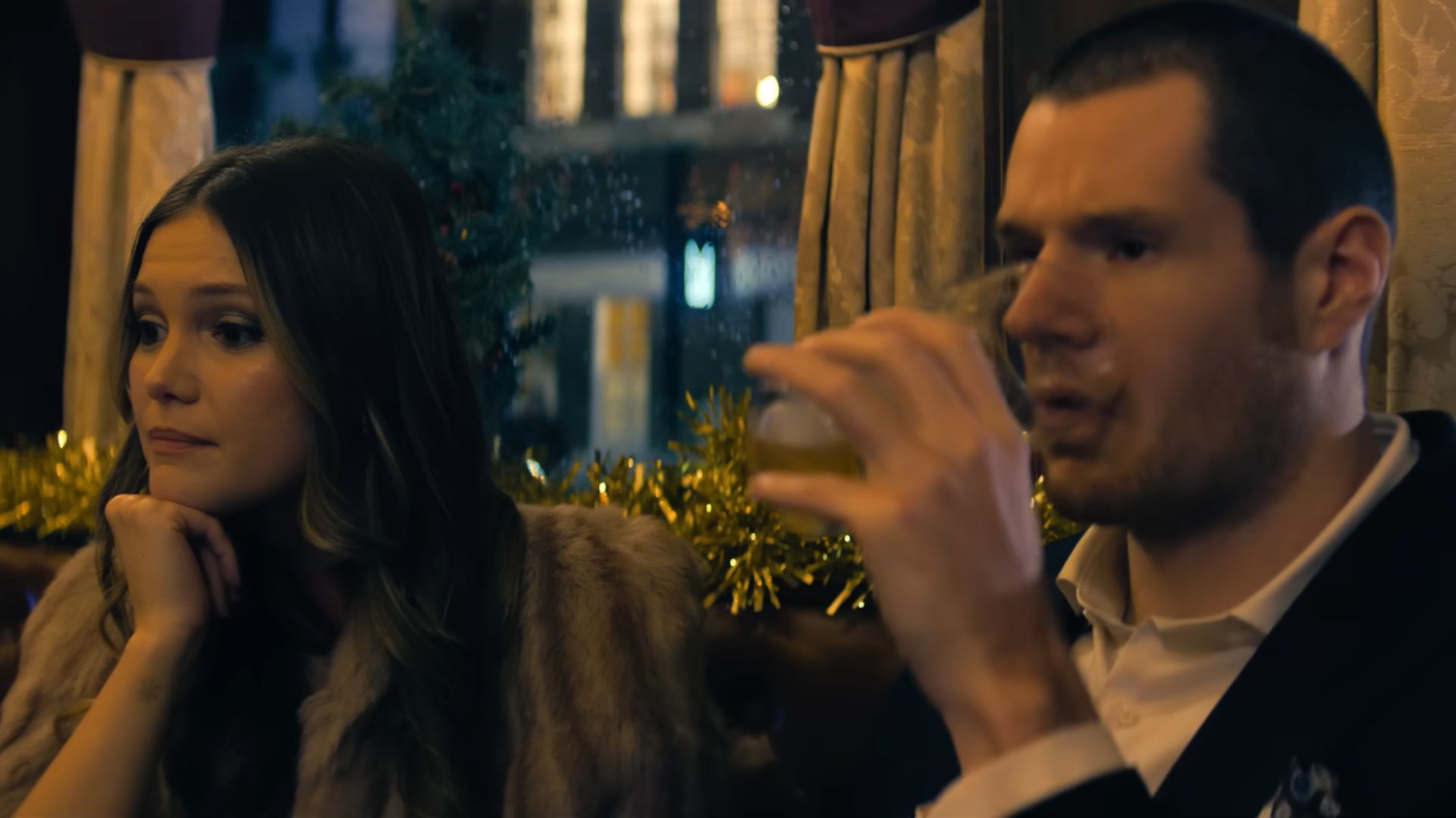 Nick drinks from a glass and Sophia sits besides him, thinking something