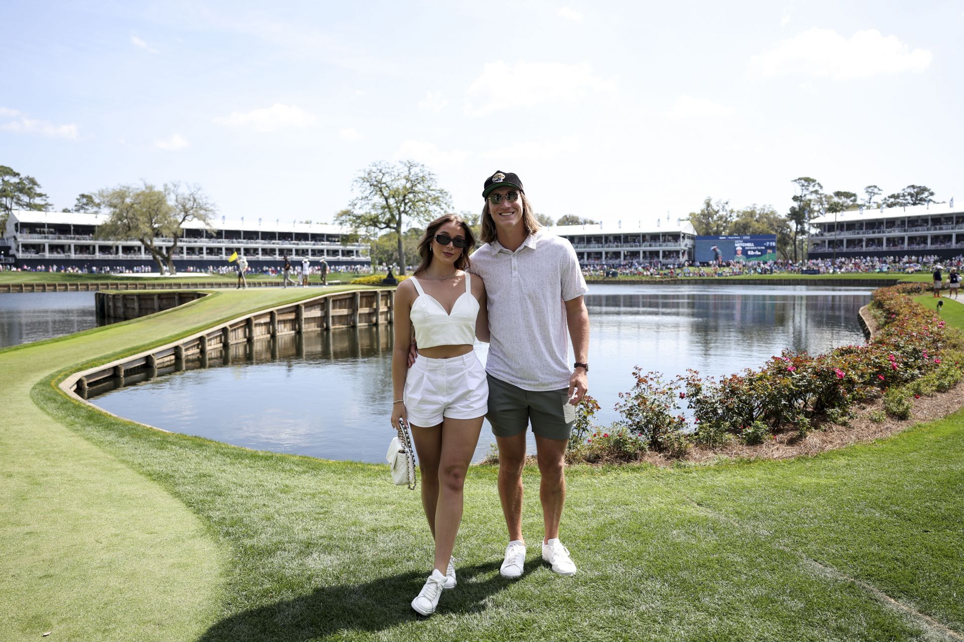 Trevor Lawrence and his wife Marissa Mowry smile for a photo near the 17th green during the second round of THE PLAYERS Championship at Stadium Course at TPC Sawgrass on March 15, 2024 in Ponte Vedra Beach, Florida - Source: Getty